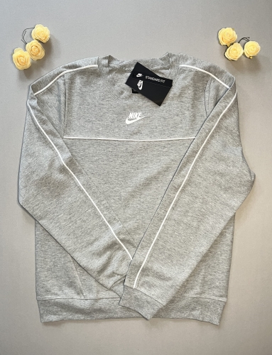 Postaw na wygodę w szarym wydaniu! Klasyczna bluza Nike o kroju crewneck z subtelnymi białymi lampasami na rękawach. Idealna do sportowych i casualowych stylizacji. Sprawdź!