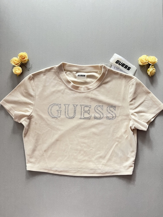 Dodaj blasku swojej szafie z beżowym t-shirtem Guess. Krótki krój,miękki materiał i efektowne logo z cyrkonii. Idealna do jeansów i spódnic. Sprawdź nową kolekcję Guess!